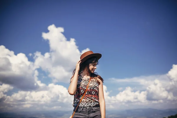 在阳光明媚的群山中 在天空云的背景下 旅行者时髦的女孩站在帽子里 文本的空间 快乐的大气时刻 旅行和流浪 — 图库照片