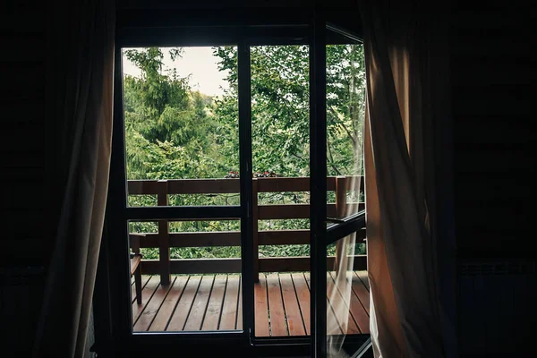 beautiful view from window on porch on trees in woods. cottage balcony with view on forest in mountains. atmospheric moment. summer vacation. rural country relax time