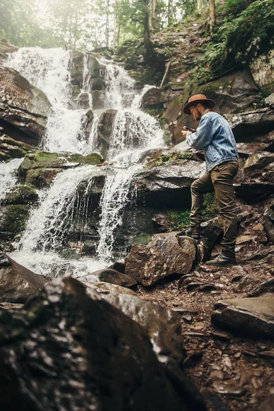 Man Van Stijlvolle Hipster Muts Met Fotocamera Opnamen Van Waterval — Stockfoto