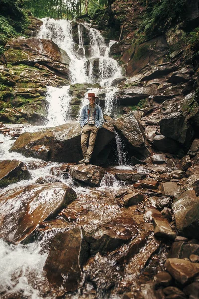 Stijlvolle Hipster Man Hat Met Fotocamera Permanent Bij Waterval Forest — Stockfoto