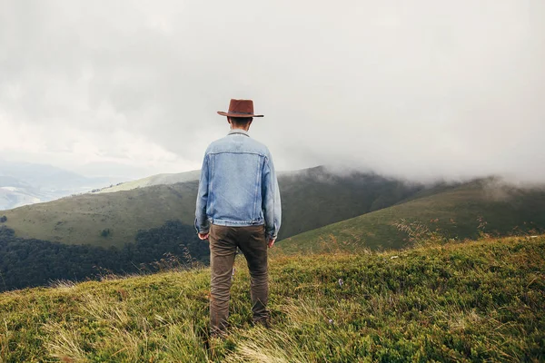 时尚的旅行者在帽子走在阳光明媚的山上的薄雾云 旅行和流浪概念 文本的空间 快乐的时髦的家伙旅行 — 图库照片