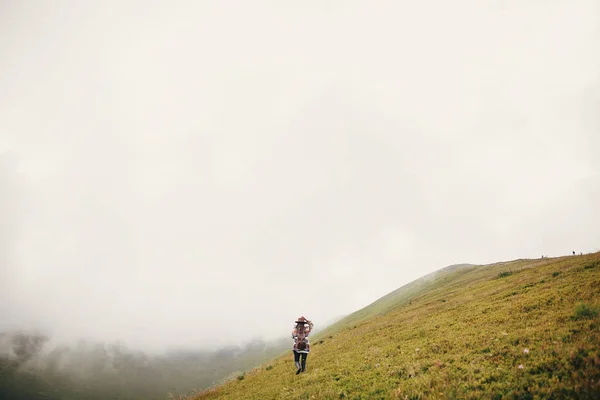 Stylish Traveler Girl Holding Hat Backpack Windy Hair Walking Mountains — Stock Photo, Image