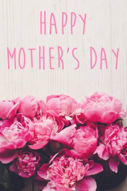 mutlu anneler günü metin pembe peonies buket rustik Beyaz ahşap arka planda üstten görünüm üzerinde. çiçek tebrik kartı kavramı, düz yatıyordu. Anneler günü. Dikey bahar görüntü