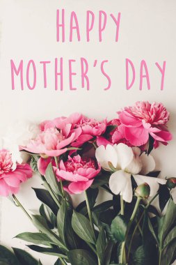 mutlu anneler günü metin pembe peonies buket rustik Beyaz ahşap arka planda üstten görünüm üzerinde. çiçek tebrik kartı kavramı, düz yatıyordu. Anneler günü. Dikey bahar görüntü