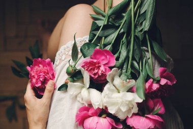 moody sabah beyaz bohem içinde şık kadın ayak üzerinde güzel peonies çiçek Üstten Görünüm.