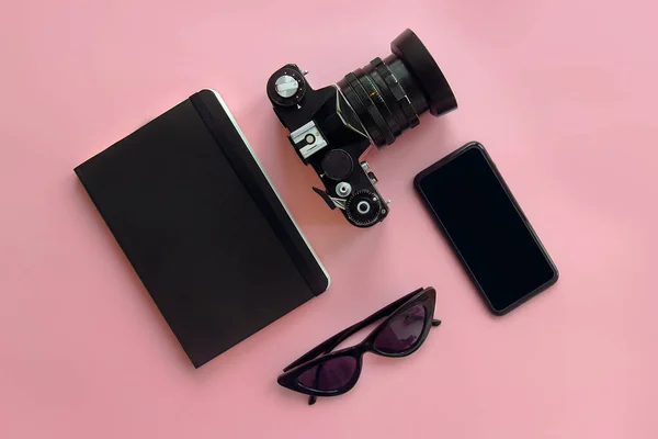 时尚的黑色太阳镜 智能手机 照片相机和笔记本在粉红色背景 现代的时髦形象 文本的空间 — 图库照片