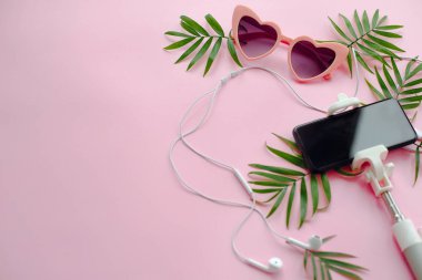 şık pembe güneş gözlüğü, pembe telefon üstünde selfie sopa, kulaklık ve yeşil palmiye bırakır. Yaz düz yatıyordu. yaz tatil kavramı, metin için yer. seyahat için zaman