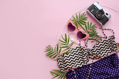 şık pembe güneş gözlüğü, modern mayo, fotoğraf makinesi, kulaklık ve pembe bir arka plan üzerinde yeşil palmiye yaprakları, yaz düz yatıyordu.