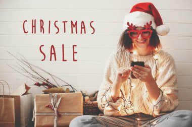 Christmas Sale text sign on stylish happy girl in santa hat look