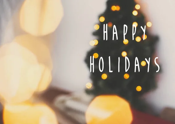 Happy Holidays text sign on blurred christmas tree and golden li — Stock Photo, Image