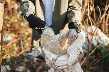 Çevre aktivisti parkta kirli plastik şişeleri topluyor. Kadın ha
