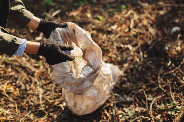 Egy önkéntes koszos műanyag palackokat szed fel a parkban. Női kéz. — Stock Fotó