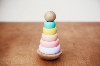 Tahta masadaki çocuk için şık bir tahta oyuncak. Yüzüklü modern ahşap piramit. Eko dostu, yeni yürümeye başlayan çocuk için plastik oyuncaklar. Metin için boşluk
