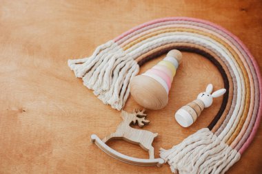 Bebek için çevre dostu plastik oyuncaklar. Tahta masadaki çocuk için şık tahta oyuncaklar. Modern renkli ahşap piramit halkalar, ahşap tavşan ve makrome gökkuşağı.