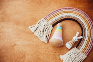 Bebek için çevre dostu plastik oyuncaklar. Tahta masadaki çocuk için şık tahta oyuncaklar. Yüzüklü, ahşap piramit, ahşap tavşan ve makrome gökkuşağı. Boşluk