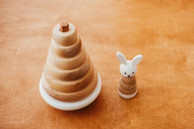 Çocuk için çevre dostu, plastik ücretsiz eğitim oyuncakları. Tahta masadaki çocuk için şık tahta oyuncaklar. Yüzüklü ve tavşanlı modern basit ahşap piramit.