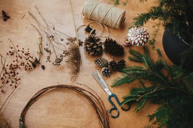 Noel çelengi yapmak. Dallar, kozalaklar, iplik, makas.