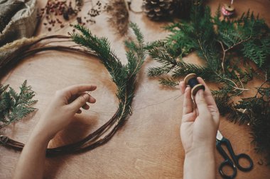 Eller iplik ve sedir dalları, çam kozalakları, makas tutuyor.