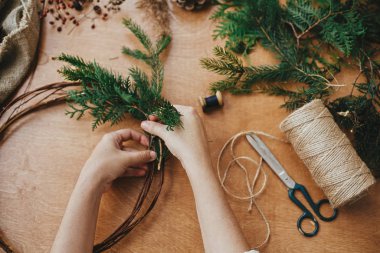 Kırsal Noel çelengi yapıyorum. Sedir dallarını tutan eller ve