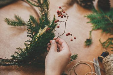 Böğürtlen tutan eller, köknar dalları, kozalaklar, iplik, makas