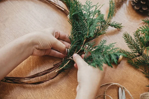 Hands holding cedar branches and pine cones, thread, scissors on — Stock Photo, Image