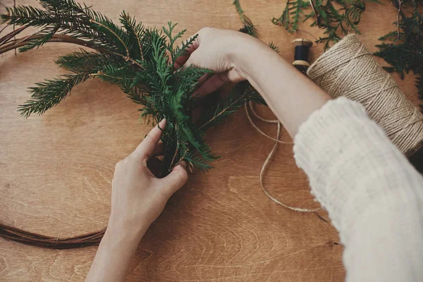 Fazendo rústico natal grinalda plana leigos. Mãos segurando branc de abeto — Fotografia de Stock