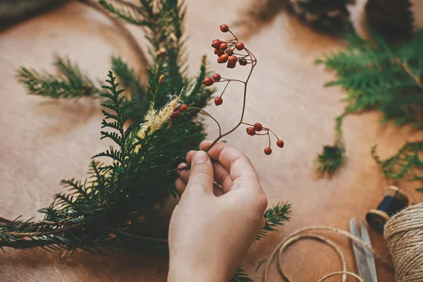 Böğürtlen tutan eller, köknar dalları, kozalaklar, iplik, makas