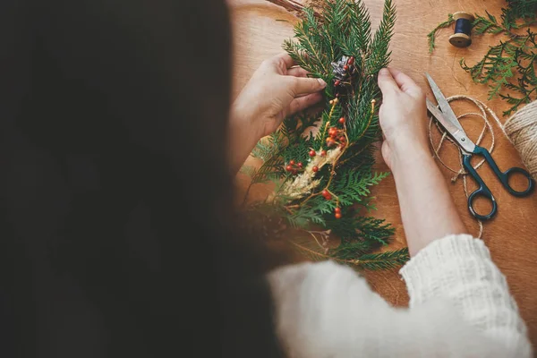 Oficina de flores de Natal. Mãos segurando ramos de abeto, cone de pinho — Fotografia de Stock
