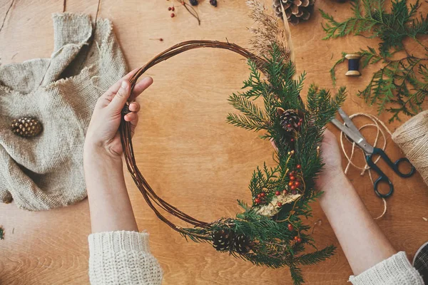 Dílna vánočních věnců. Ruce držící jedlové větve, borový kužel — Stock fotografie