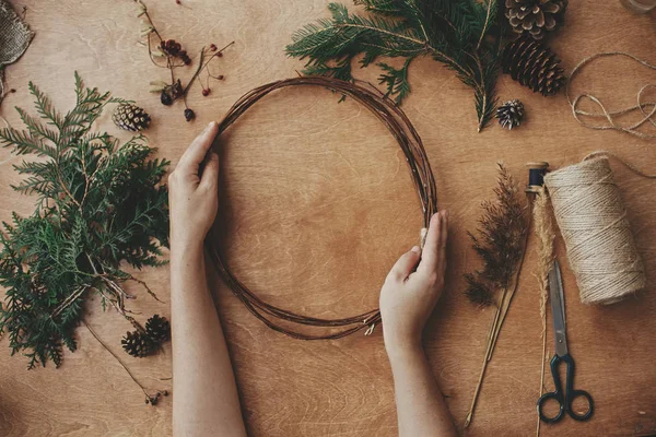 Making christmas wreath flat lay. Hands holding wooden circle an — Stock Photo, Image