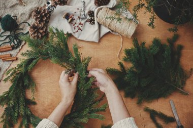 Kırsal Noel çelengi düzleştiriyor. Eller köknar dalını tutuyor