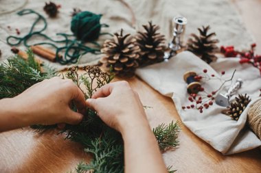Kırsal Noel çelengi yapıyorum. Bitki ve köknar sütyeni tutan eller.