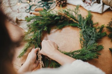 Kırsal Noel çelengi yapıyorum. Ellerinde otlar ve köknar kepeği vardı.