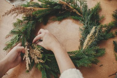 Ellerinde otlar ve köknar dalları, kozalaklar, iplik, berri
