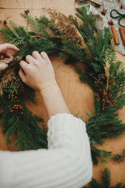 Kırsal Noel çelengi düzleştiriyor. Elleri böğürtlen tutarken