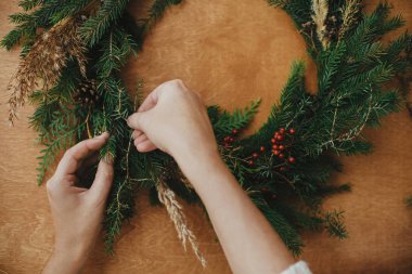 Kırsal Noel çelengi düzleştiriyor. Eller köknar dalını tutuyor