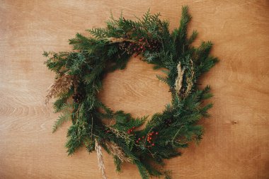 Ahşap masada düz bir şekilde duran yaratıcı kırsal noel çelengi. Chri.