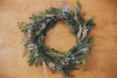 Ahşap masada düz bir şekilde duran yaratıcı kırsal noel çelengi. Chri.