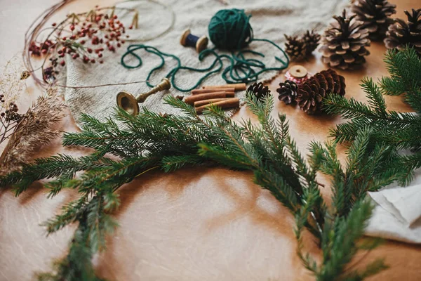 Haciendo una corona de Navidad. Ramas de abeto, conos de pino, hilo, berri —  Fotos de Stock