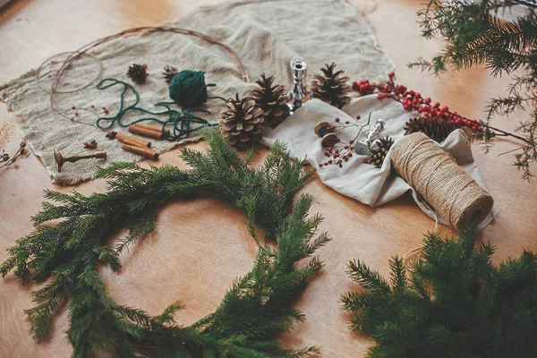 Haciendo una corona de Navidad. Ramas de abeto, conos de pino, hilo, berri — Foto de Stock