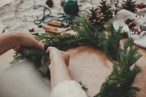 Making rustic Christmas wreath. Hands holding fir branches, and — Stock Photo, Image