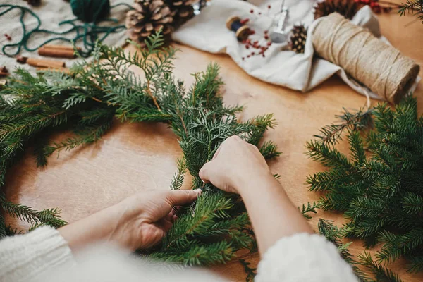 Making rustic Christmas wreath. Hands holding fir branches, and — Stock Photo, Image