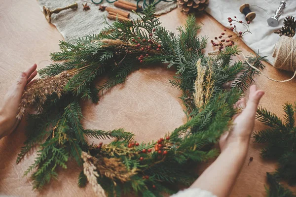 Corona rústica de Navidad. Manos sosteniendo corona de Navidad con abeto —  Fotos de Stock