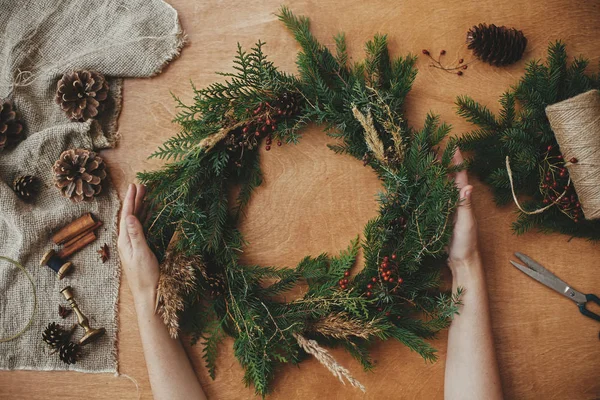Rustic Christmas wreath, flat lay. Hands holding christmas wreat — Stock Photo, Image
