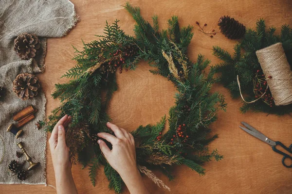 Hände halten Weihnachtskranz mit Tannenzweigen, Beeren, Kiefern — Stockfoto
