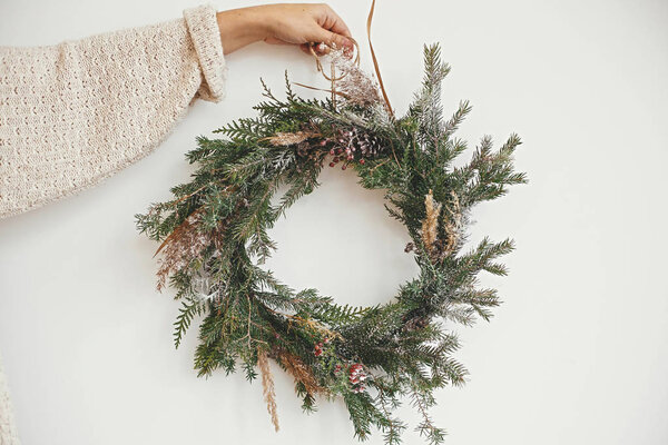 Hipster girl in white sweater holding rural christmas wreath wit