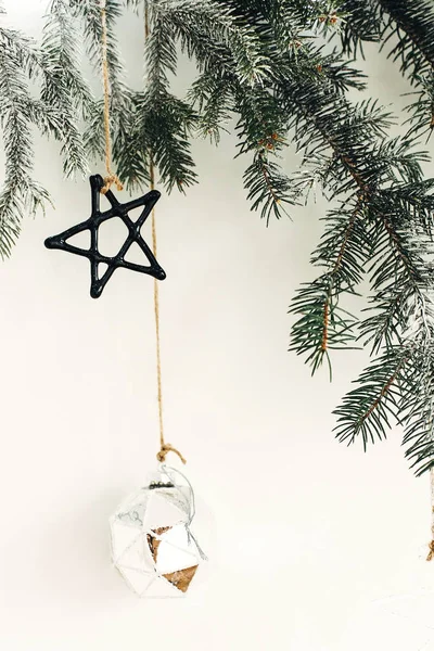 Stylish christmas ornaments on fir branch hanging on white wall. — Stock Photo, Image