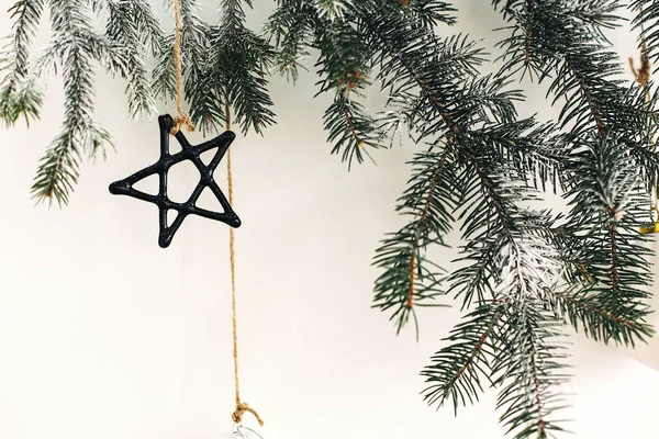 Stylové vánoční ozdoby na jedlové větvi zavěšené na bílé stěně. — Stock fotografie