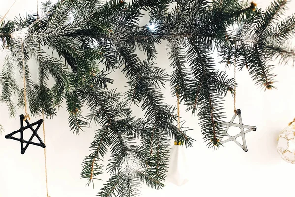 挂在白墙上的冷杉枝上的花哨的圣诞饰品. — 图库照片