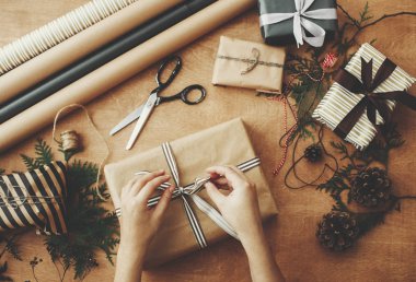 Mutlu Noeller, düz yatış. Eller şık bir Noel hediyesi paketliyor.